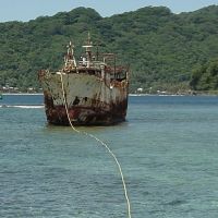 A grounded derelict vessel with a pumping line coming from it.